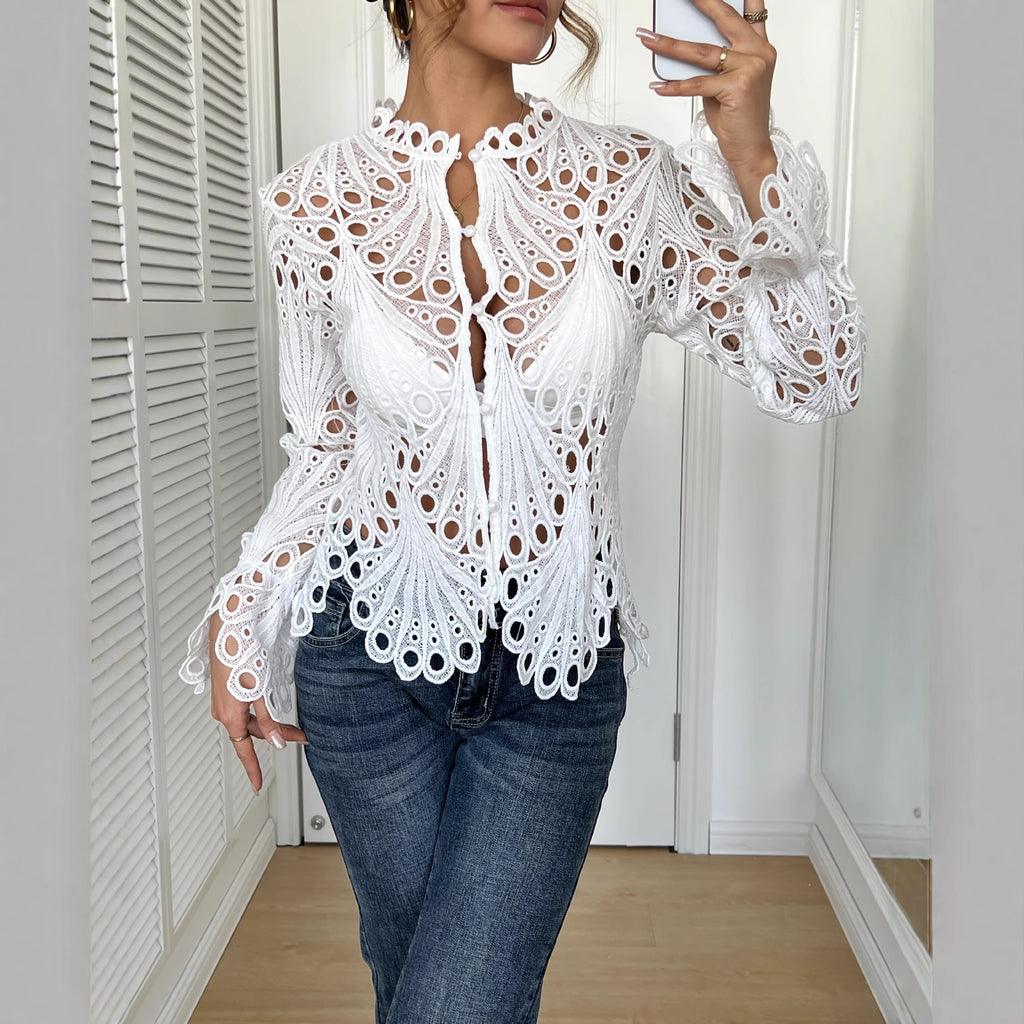 Person wearing a white lace top and blue jeans indoors.