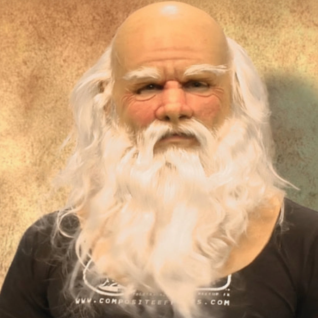 A bald man wearing a long white synthetic beard and white hair, photographed against a textured tan wall. A black T-shirt is visible at the bottom, and there is a faint Chinese watermark across the center.