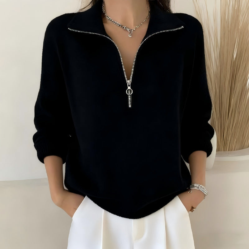Person wearing a black zip-up sweatshirt with a neutral background