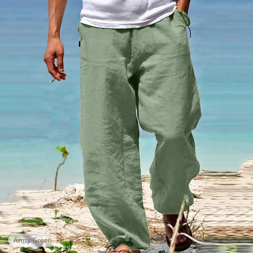Person wearing green pants standing on a beach with clear blue water in the background