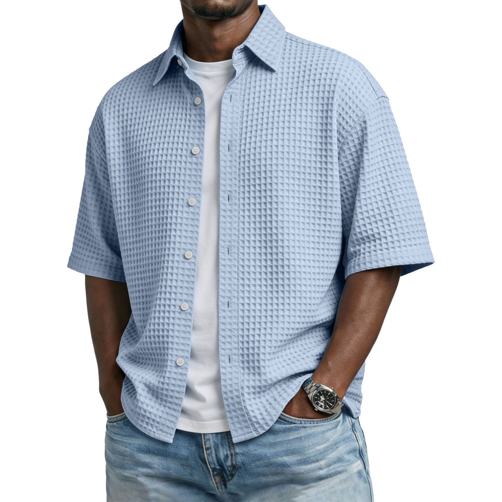 Man wearing a light blue textured short-sleeve shirt over a white t-shirt with jeans on a white background
