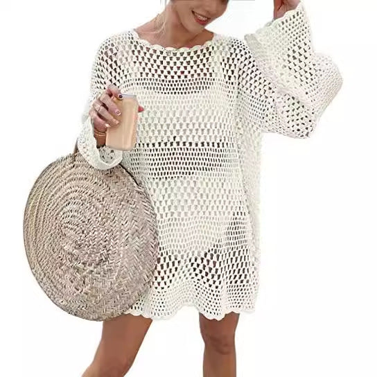 Woman wearing a white crochet cover-up with a straw bag on a white background