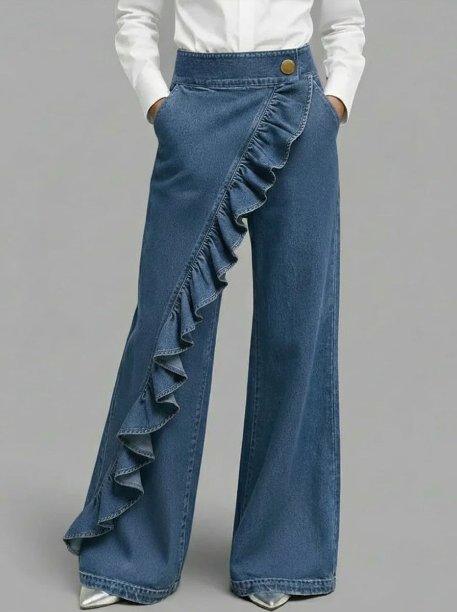 Blue denim pants with ruffled details on a gray background