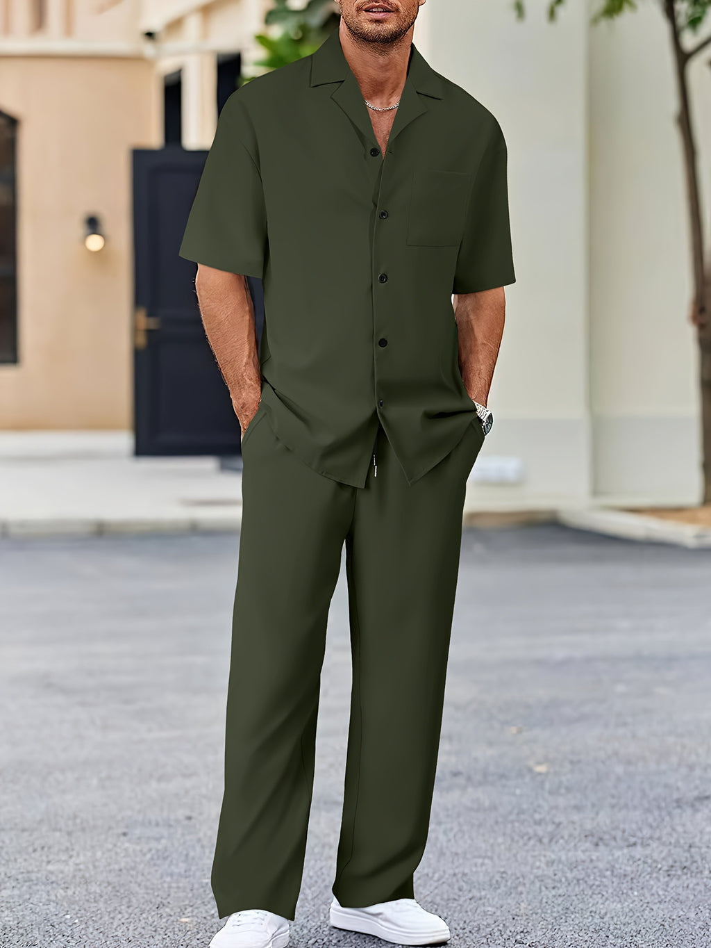 Man wearing a green outfit standing outdoors on a street.