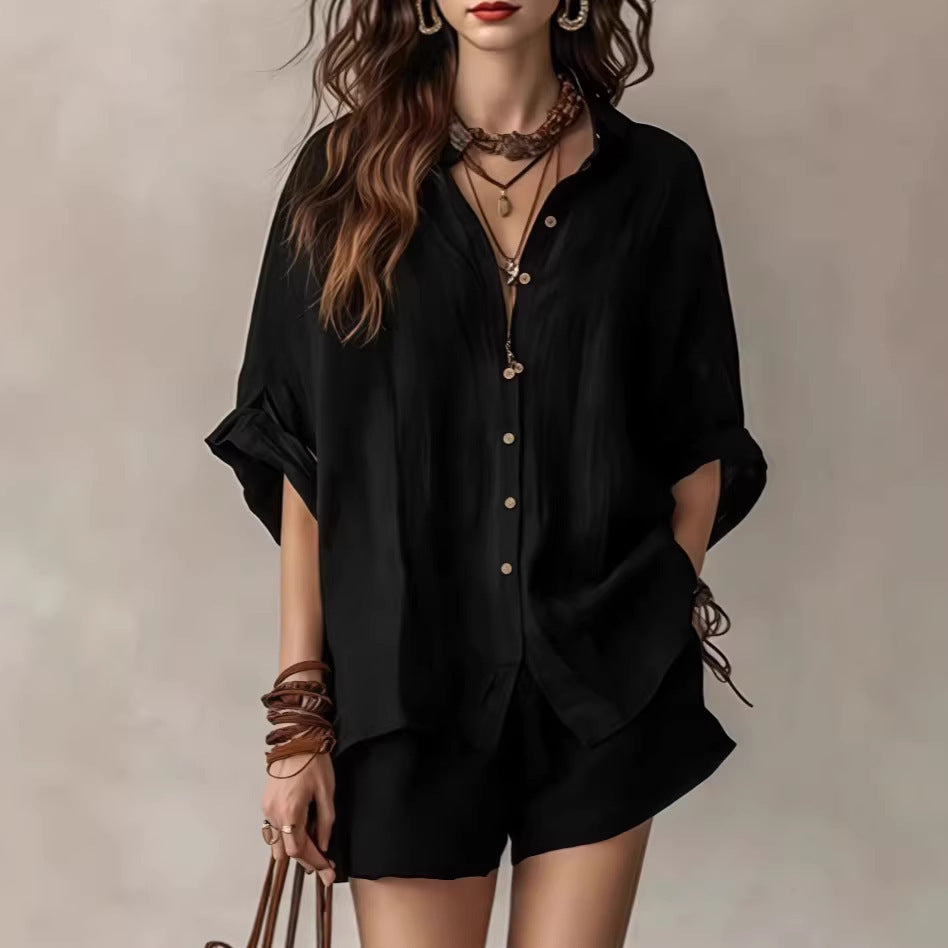 Person wearing a black outfit with layered necklaces and bracelets on a neutral background