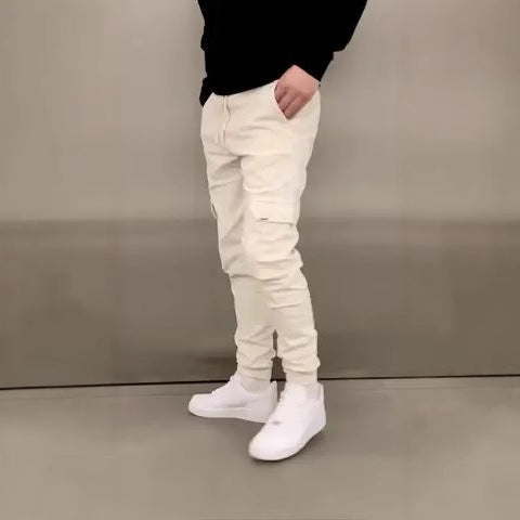 Person wearing white distressed jeans and white sneakers against a plain background