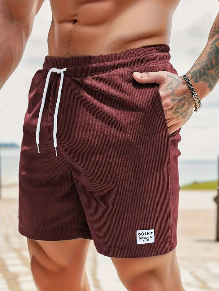 Maroon shorts with a white drawstring and brand logo worn by a person on a beach.