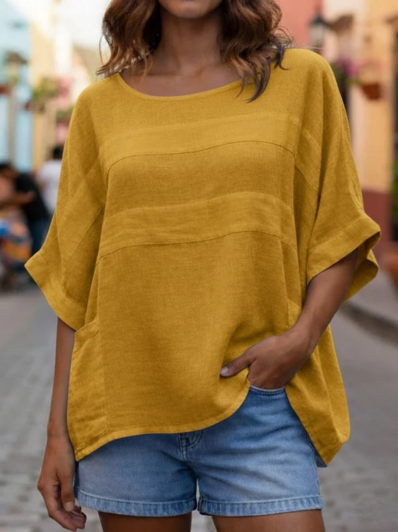 Person wearing a mustard yellow oversized shirt and denim shorts on a blurred street background