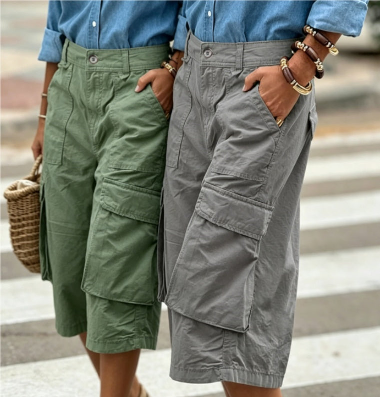 Two pairs of cargo shorts, one green and one gray, worn by people on a blurred outdoor background.
