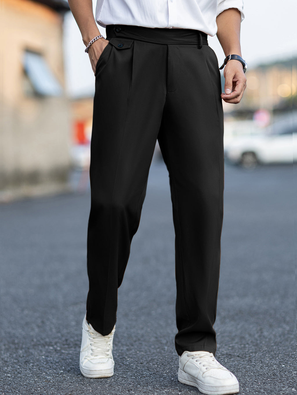 Person wearing black pants and white sneakers on a blurred street background