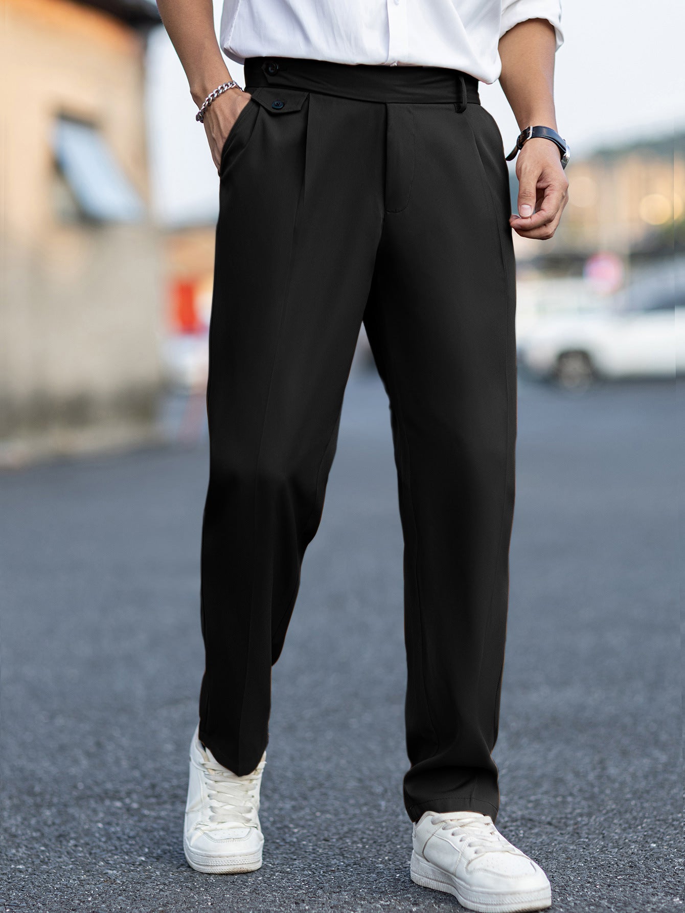 Person wearing black pants and white sneakers on a blurred street background