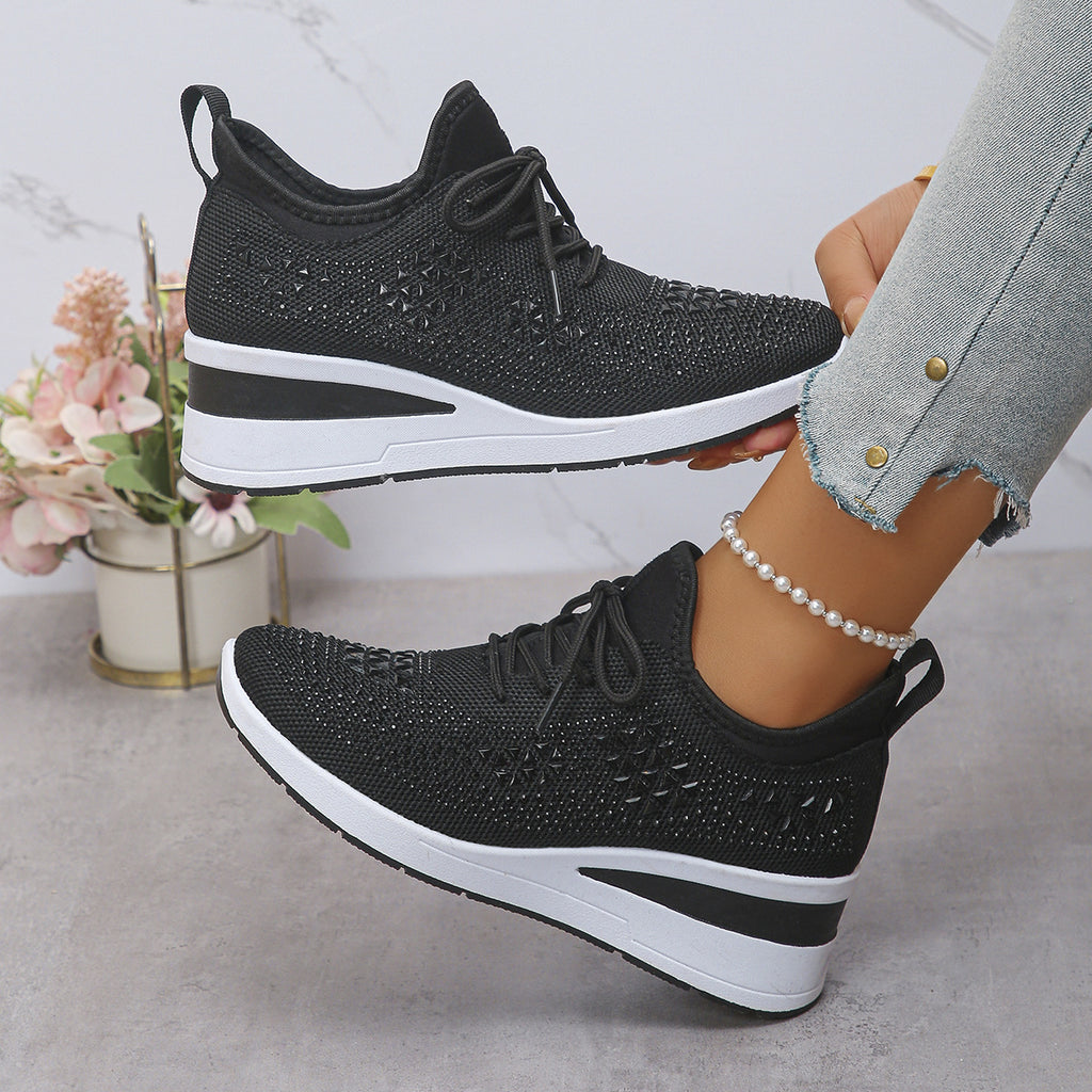 Black and white sneakers worn by a person with a light gray background