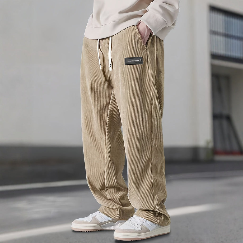 Person wearing beige corduroy pants with a small patch on a neutral background