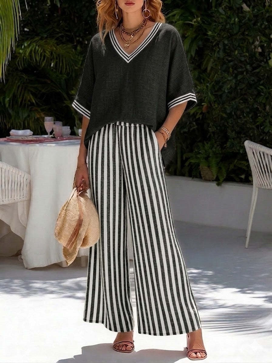 Woman wearing a black top with white stripes and black and white striped pants, standing outdoors.
