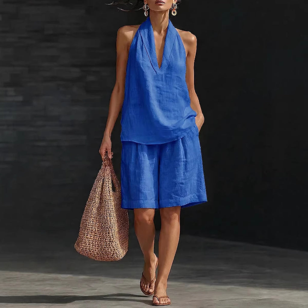 Woman in a blue outfit holding a woven bag against a dark background
