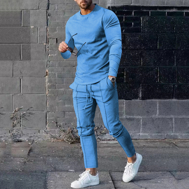 Man wearing a blue outfit standing against a brick wall.