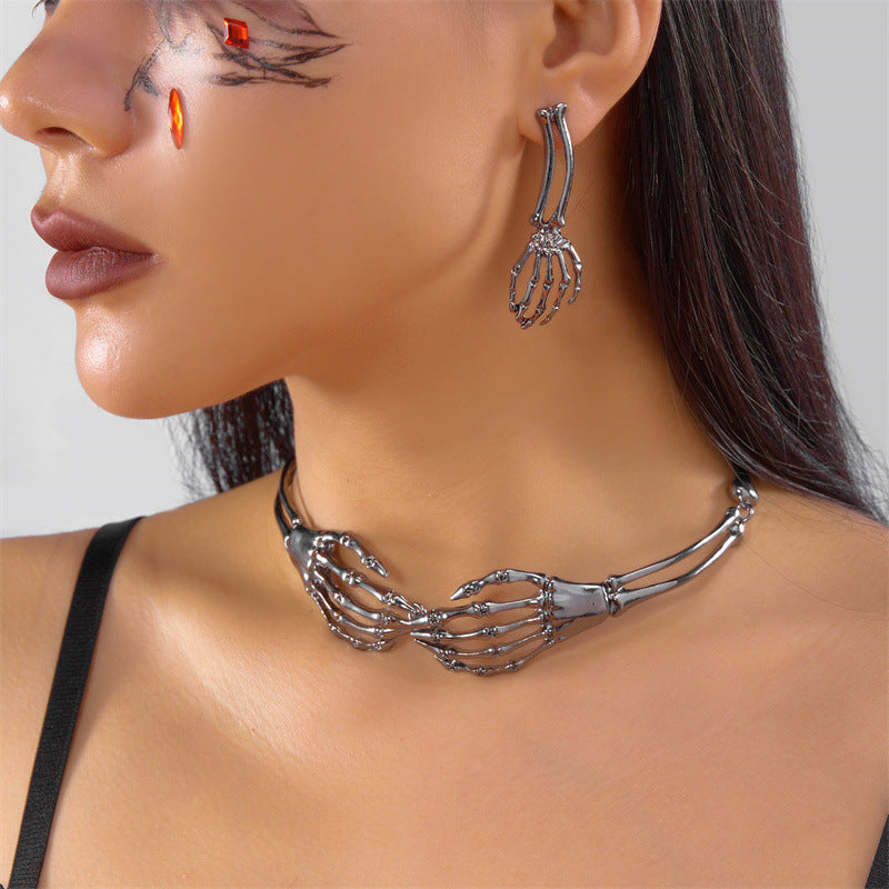 Close-up of a woman wearing skeleton hand-shaped earrings and necklace on a plain background