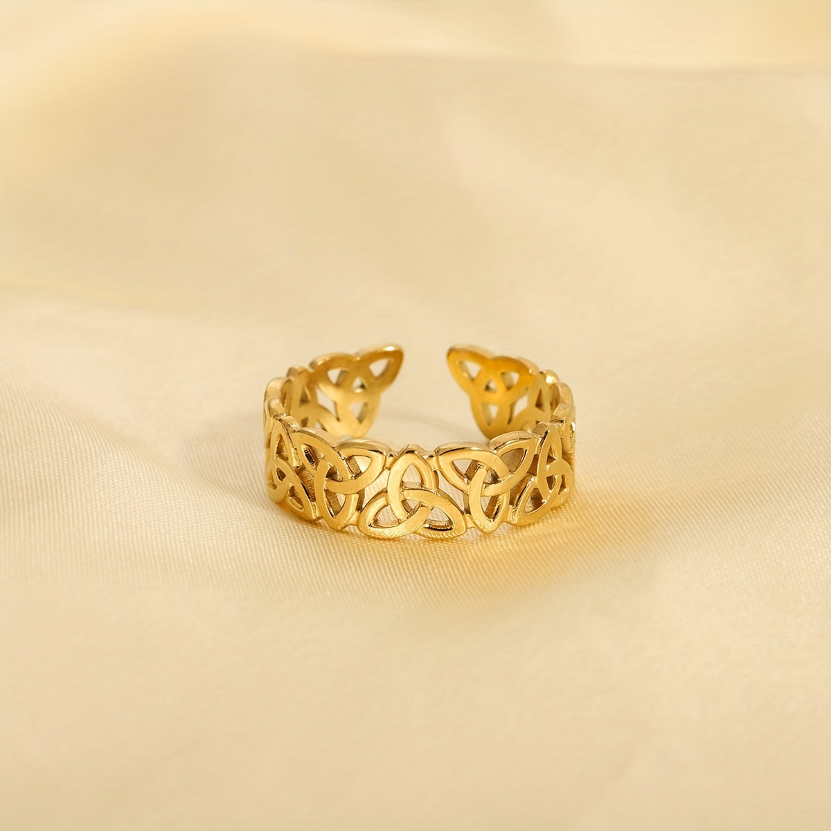 Gold openwork ring on a beige fabric background