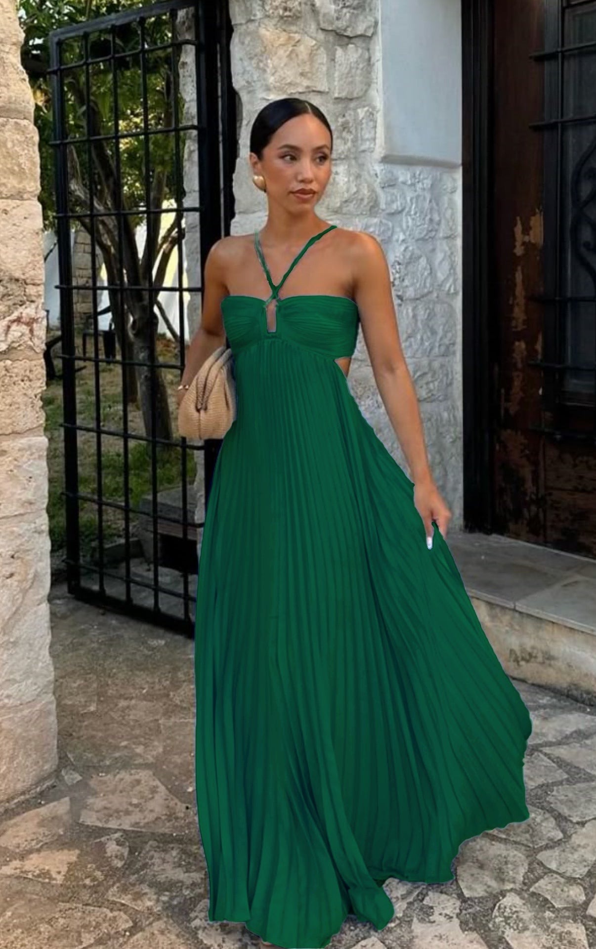 Woman in a green dress standing outdoors near a stone building.