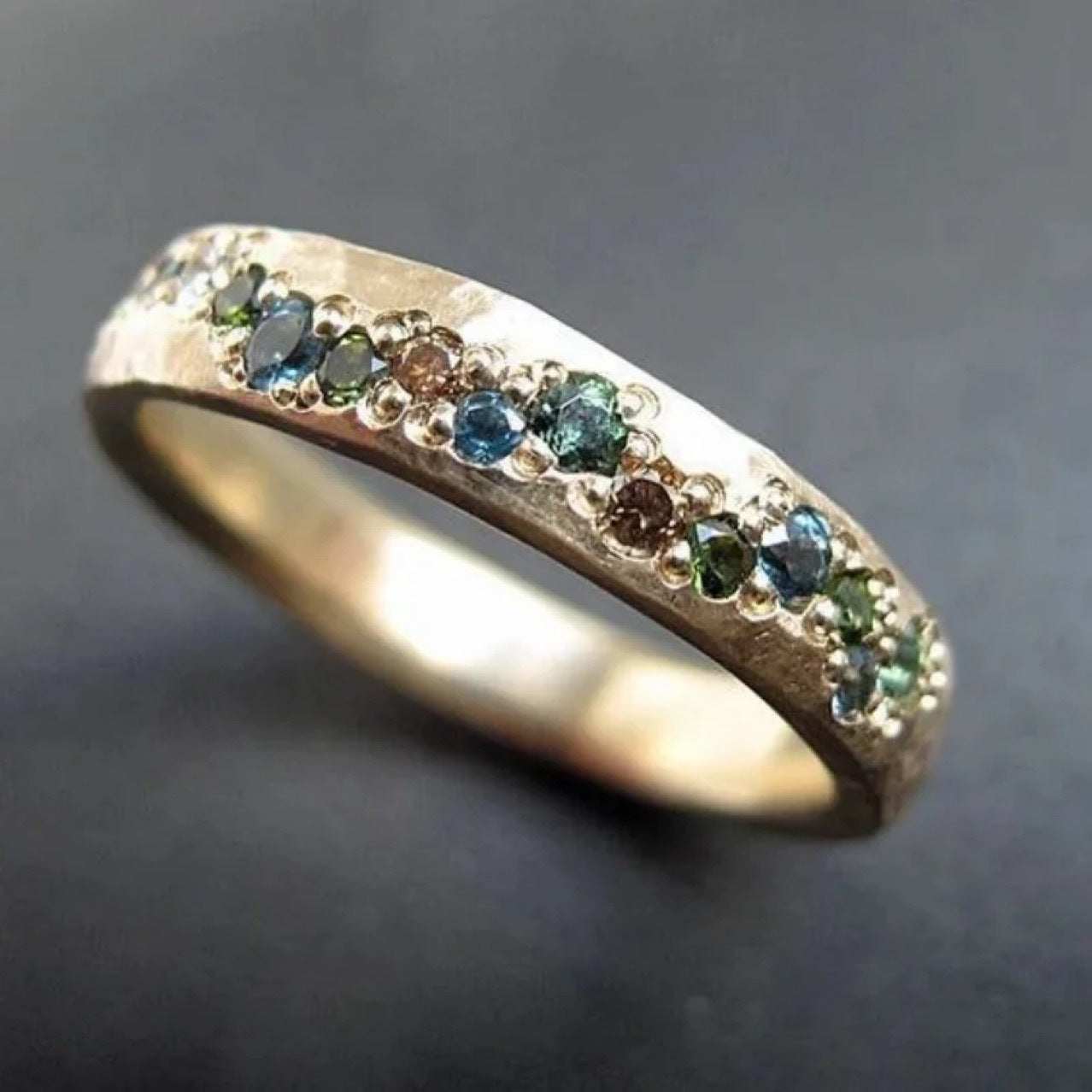 Gold ring with embedded green gemstones on a dark background
