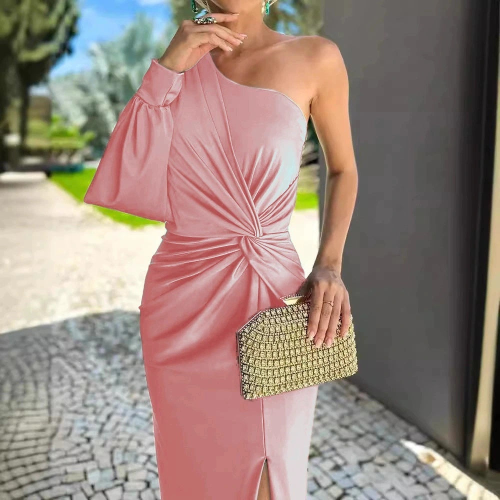 Woman in a pink one-shoulder dress holding a gold clutch outdoors.