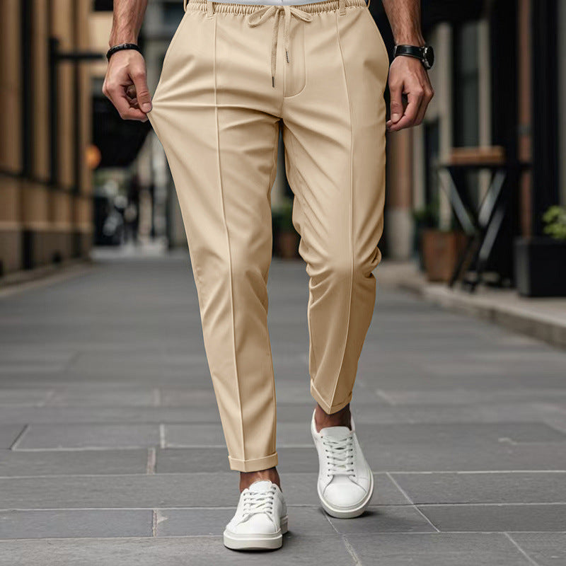 Person wearing beige pants and white sneakers on a city street.