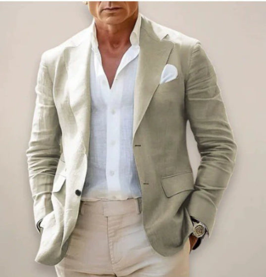 Man wearing a light green blazer over a white shirt with beige pants against a plain background