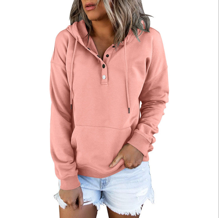 Woman wearing a pink hoodie and denim shorts on a plain background