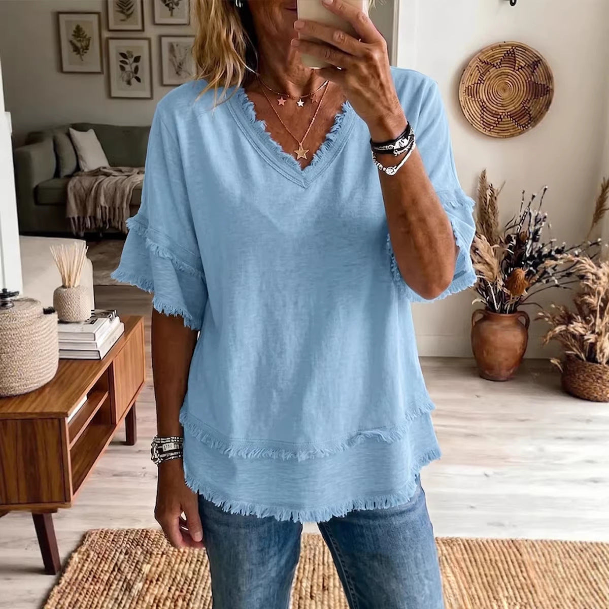 Person wearing a light blue top and jeans in a living room setting.