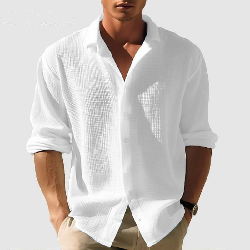 Man wearing a white textured shirt with rolled-up sleeves on a light gray background