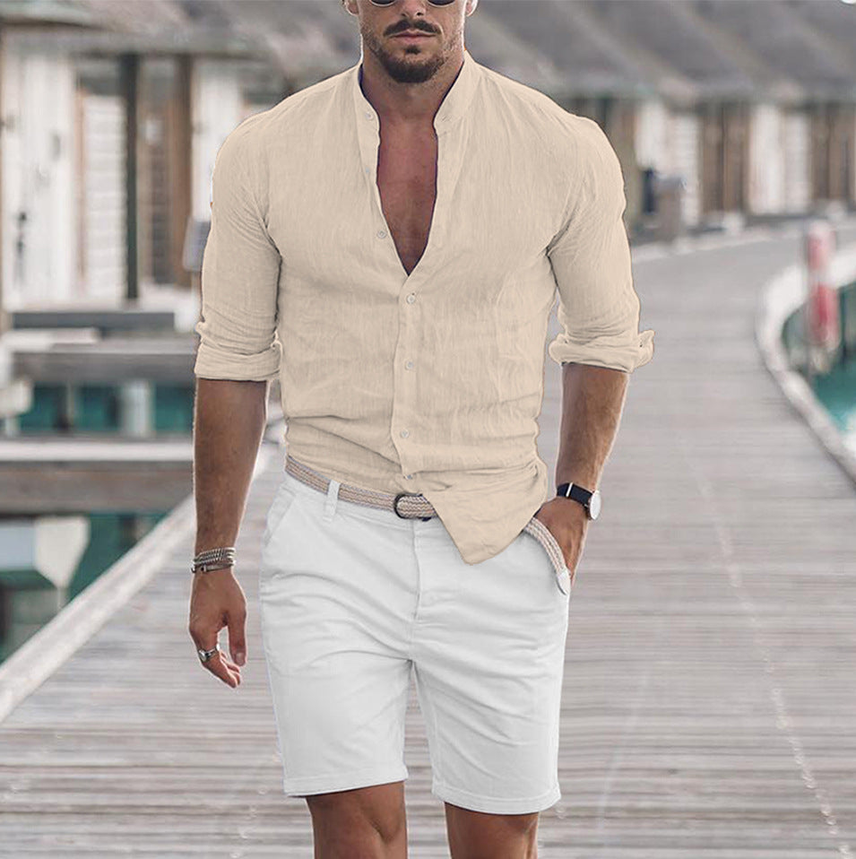 Man wearing a beige shirt and white shorts on a wooden deck.