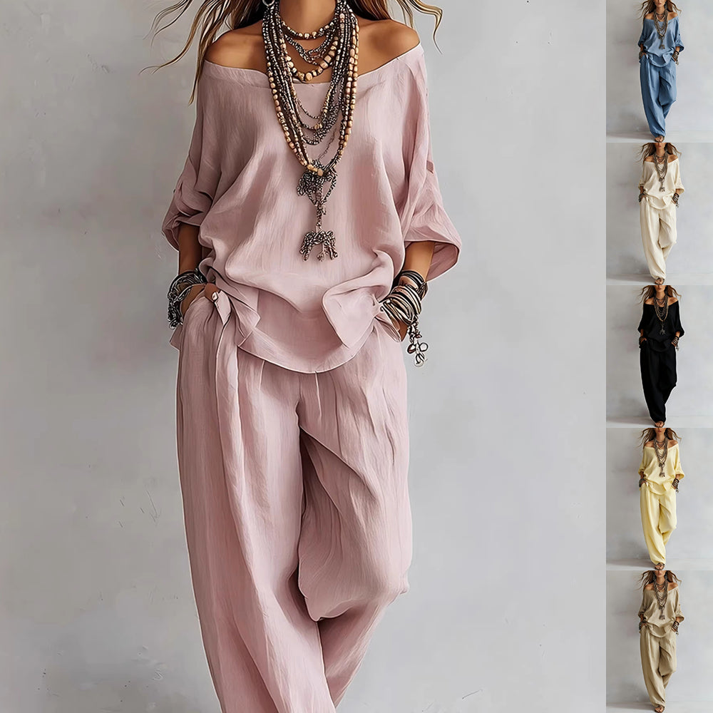 Woman wearing a pink outfit with layered necklaces on a plain background