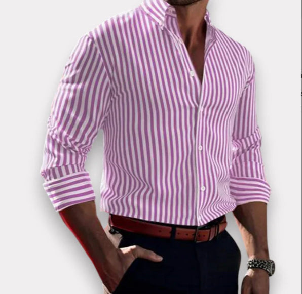 Person wearing a pink and white striped shirt with rolled-up sleeves on a plain background