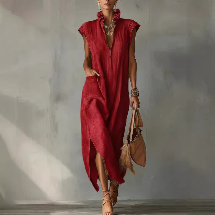 Woman in a red dress holding a brown handbag against a gray wall.