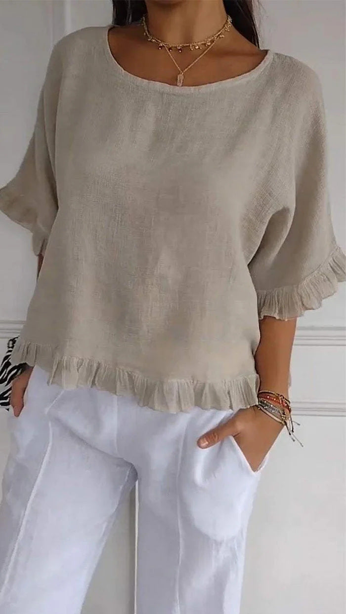 Person wearing a beige linen top and white pants against a white background