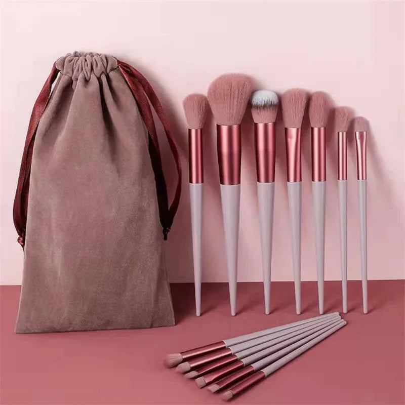 Set of pink and white makeup brushes with matching velvet pouch on a pink background