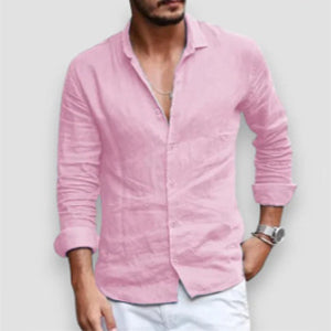 Man wearing a pink button-up shirt with rolled-up sleeves on a plain background