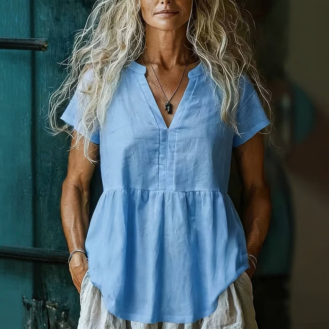 Woman wearing a blue blouse standing against a teal door.