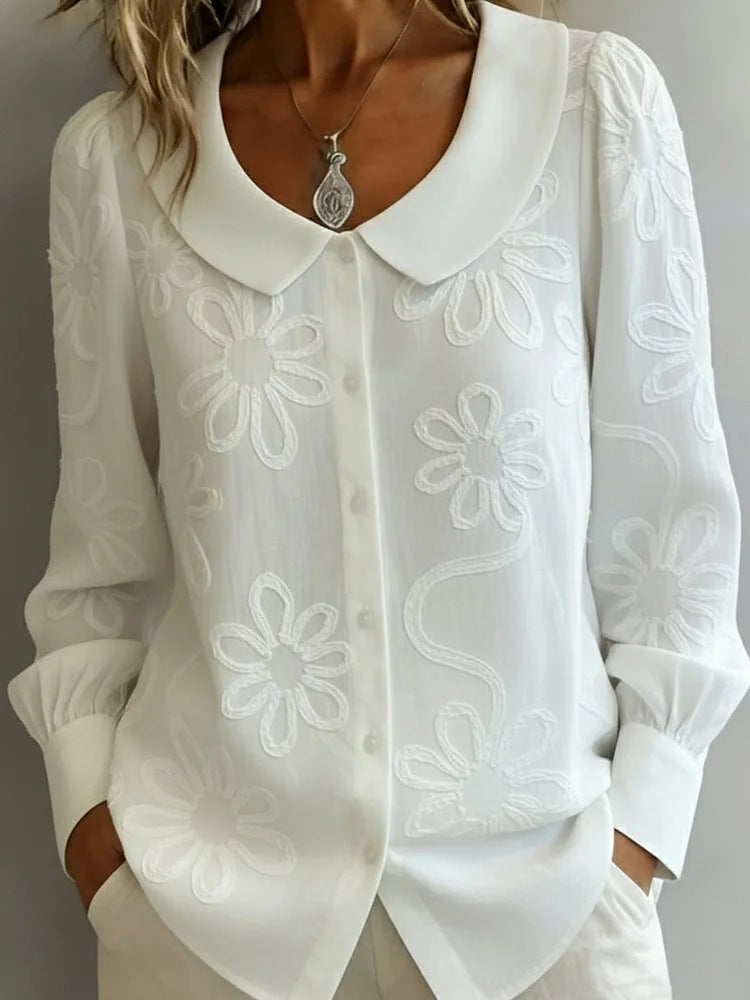 White blouse with floral embroidery on a plain background