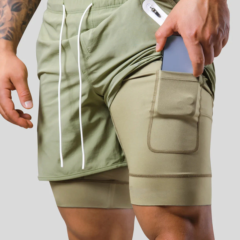 Person wearing olive green shorts with a pocket, holding a phone.