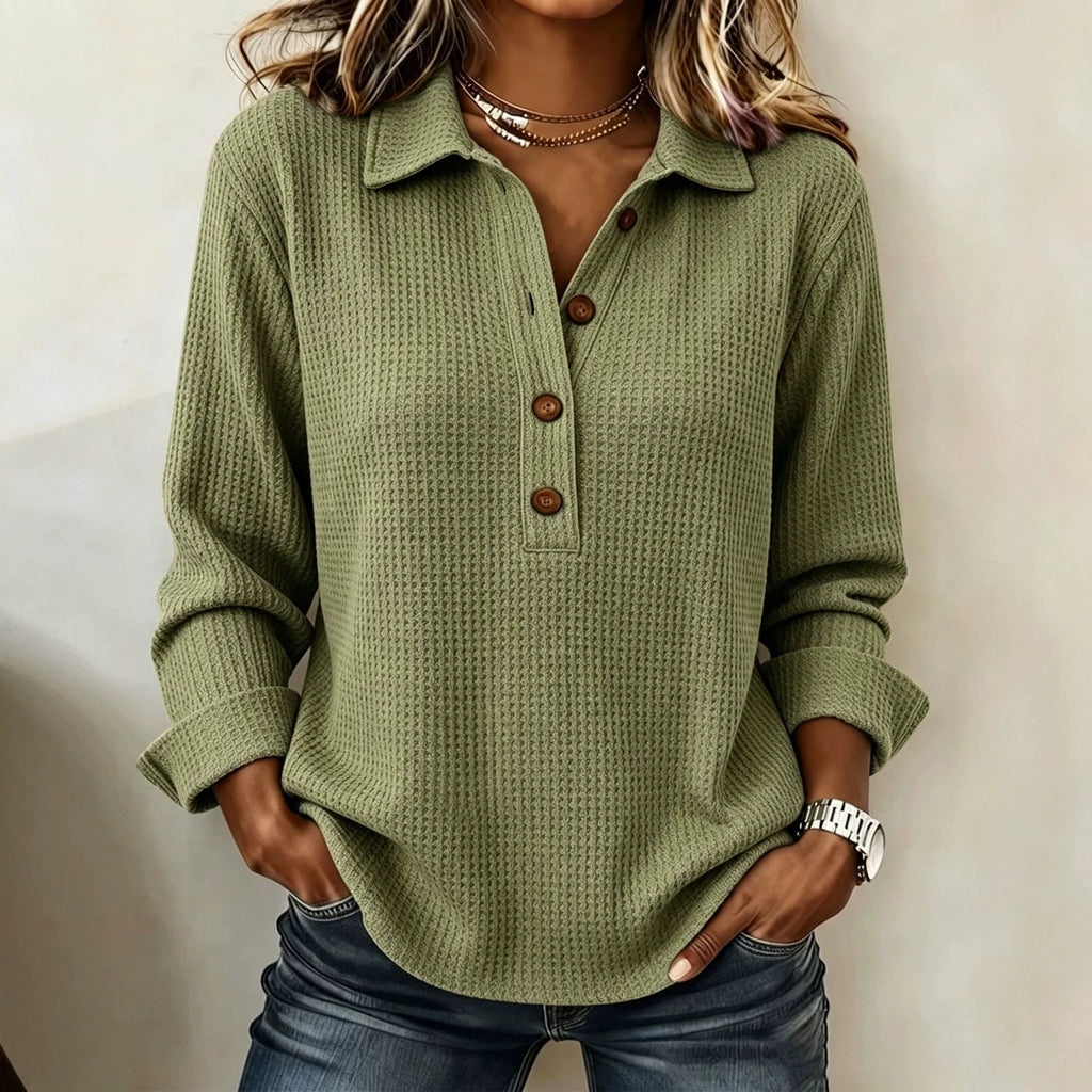 A woman wearing a sage green waffle-knit long-sleeve polo shirt with a three-button placket, paired with blue jeans.