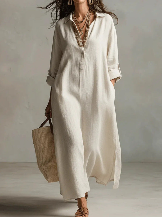 Woman wearing a long beige shirt dress holding a straw bag against a plain background