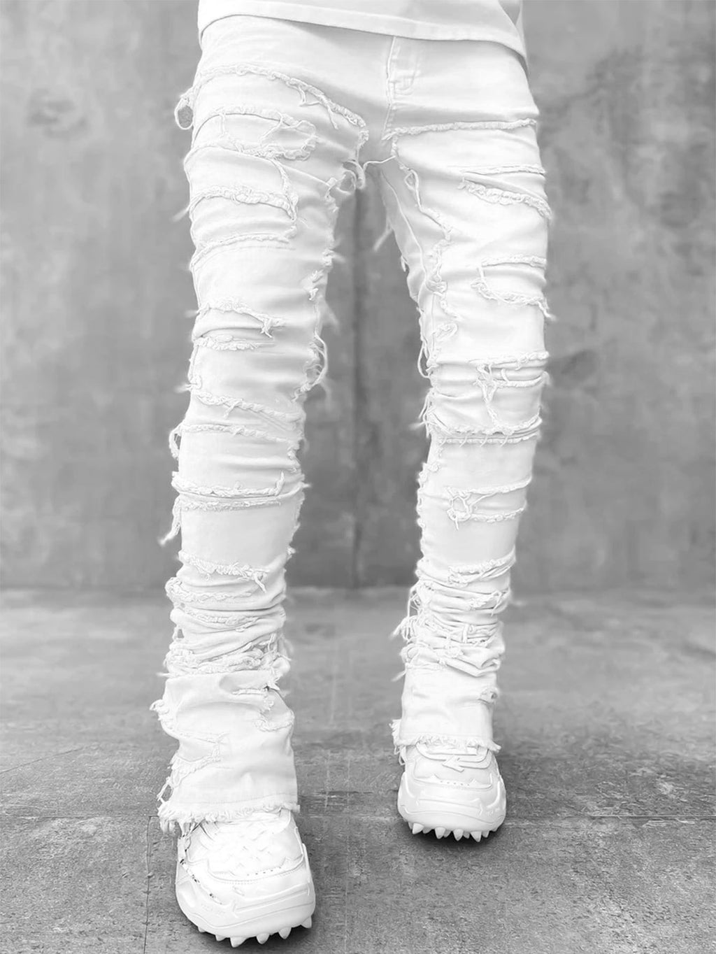 White distressed jeans worn by a person on a gray concrete floor.