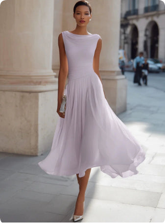 Woman in a light purple dress standing in an urban setting with classical architecture.