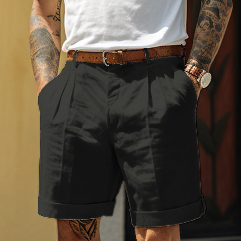 Person wearing black shorts with a white shirt and tattooed arms.