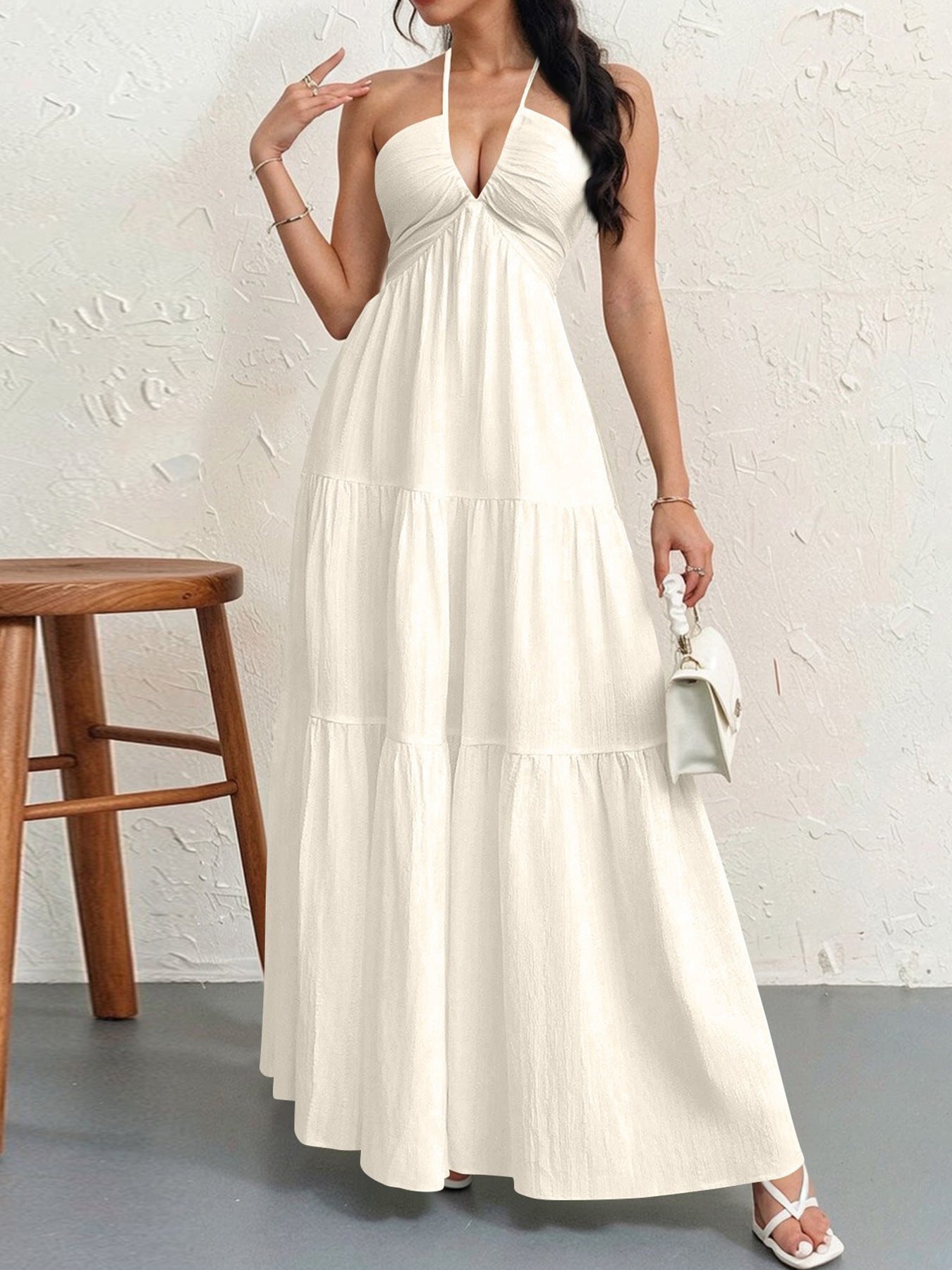 Woman wearing a white halter neck dress against a plain background