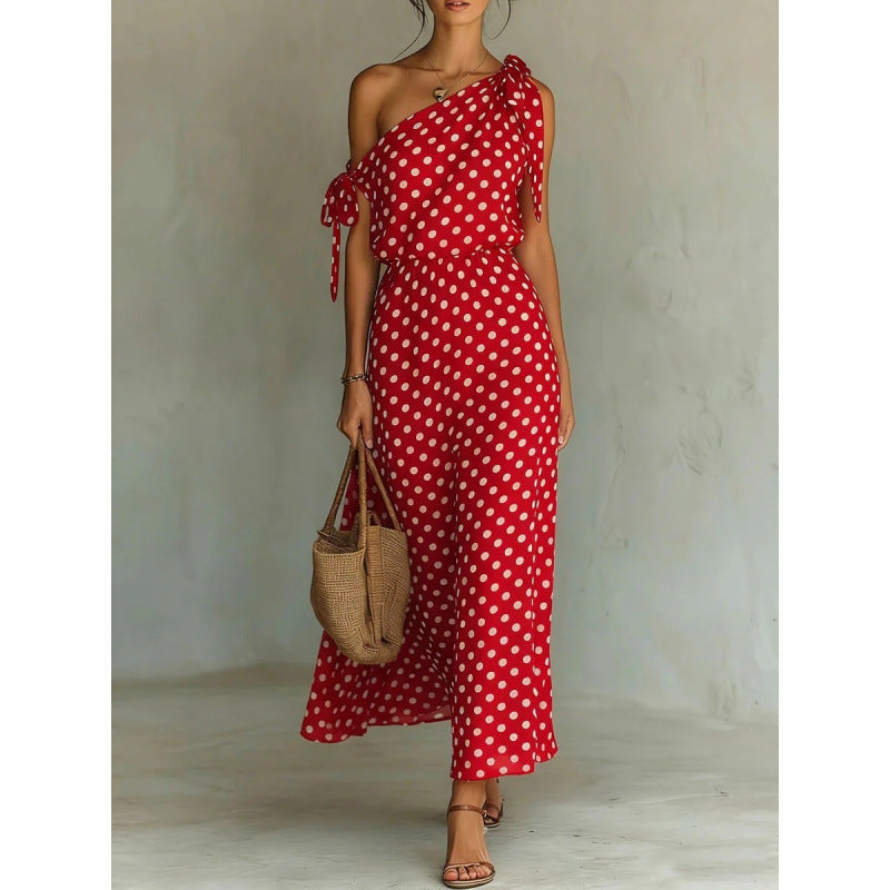 Woman wearing a red polka dot dress holding a woven bag against a neutral background