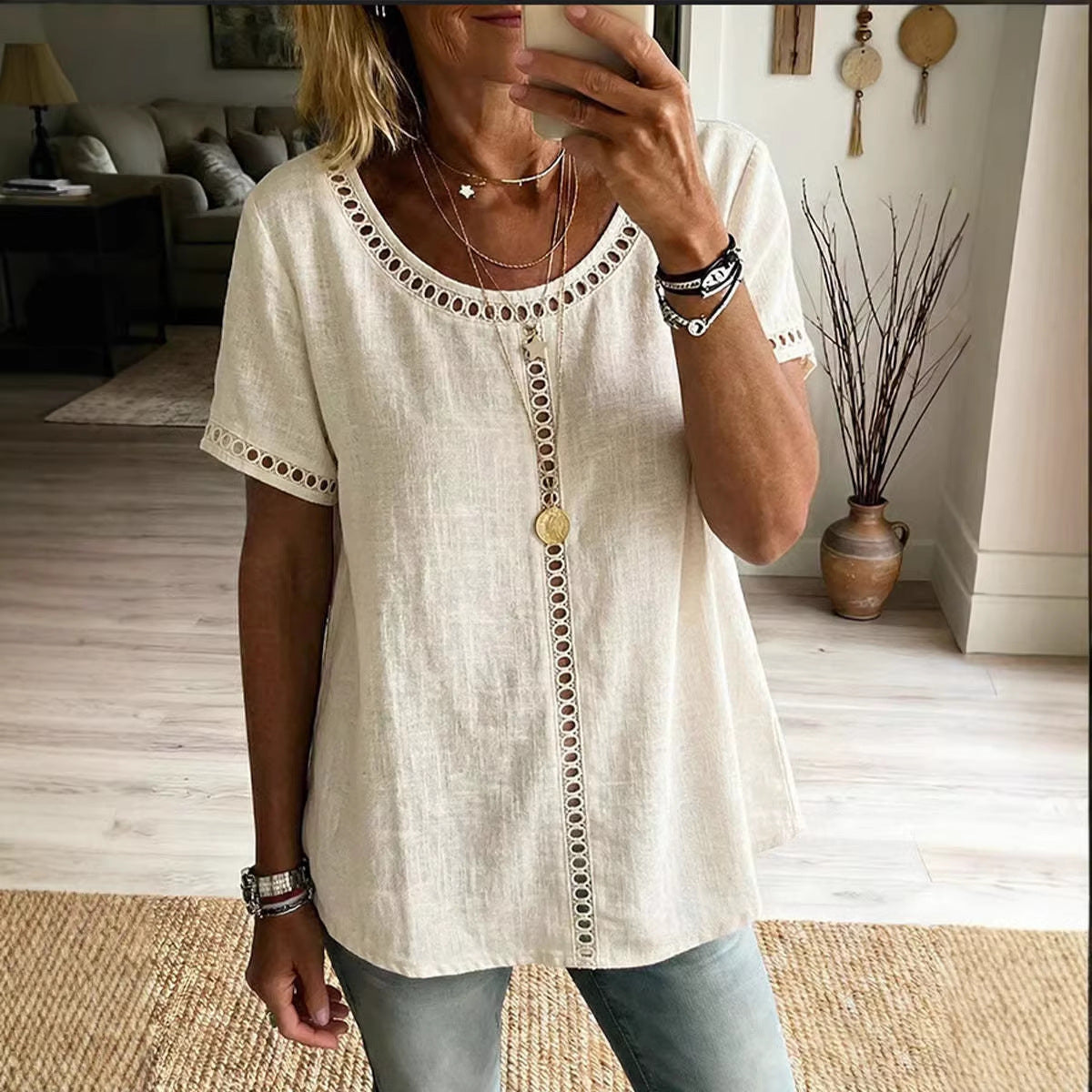 Person wearing a white blouse with decorative buttons in a living room setting.