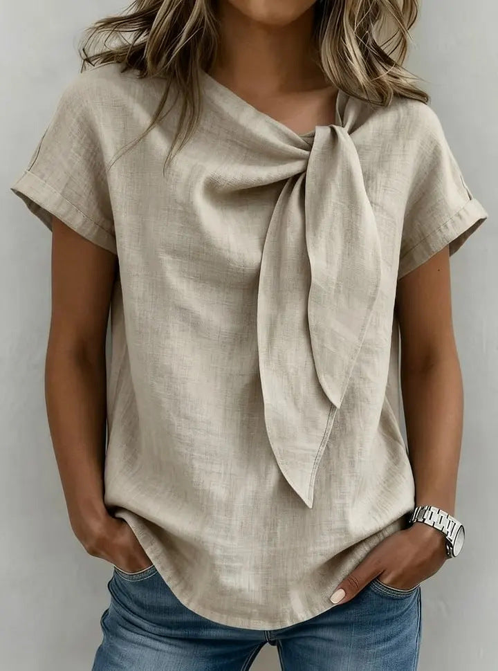 Beige linen top with a bow detail worn by a person on a plain background