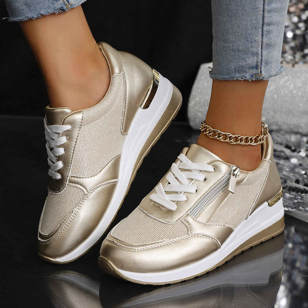 Gold sneakers with white soles worn by a person on a reflective surface.